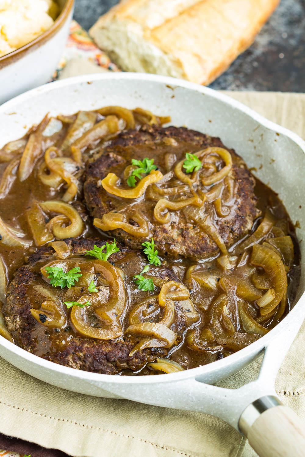 Hamburger Steak with onions and brown gravy in a sauce pan.