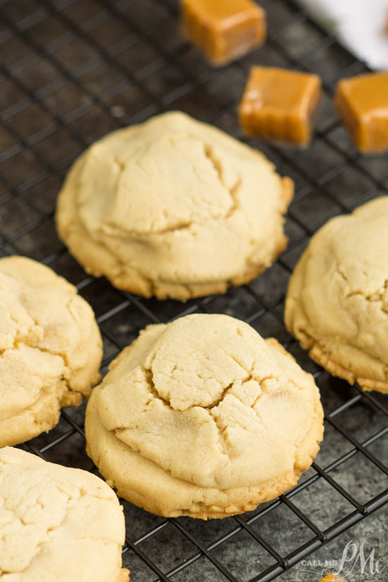 Close-up of freshly baked caramel-stuffed sugar cookies on a cooling rack, with small caramel pieces in the background.