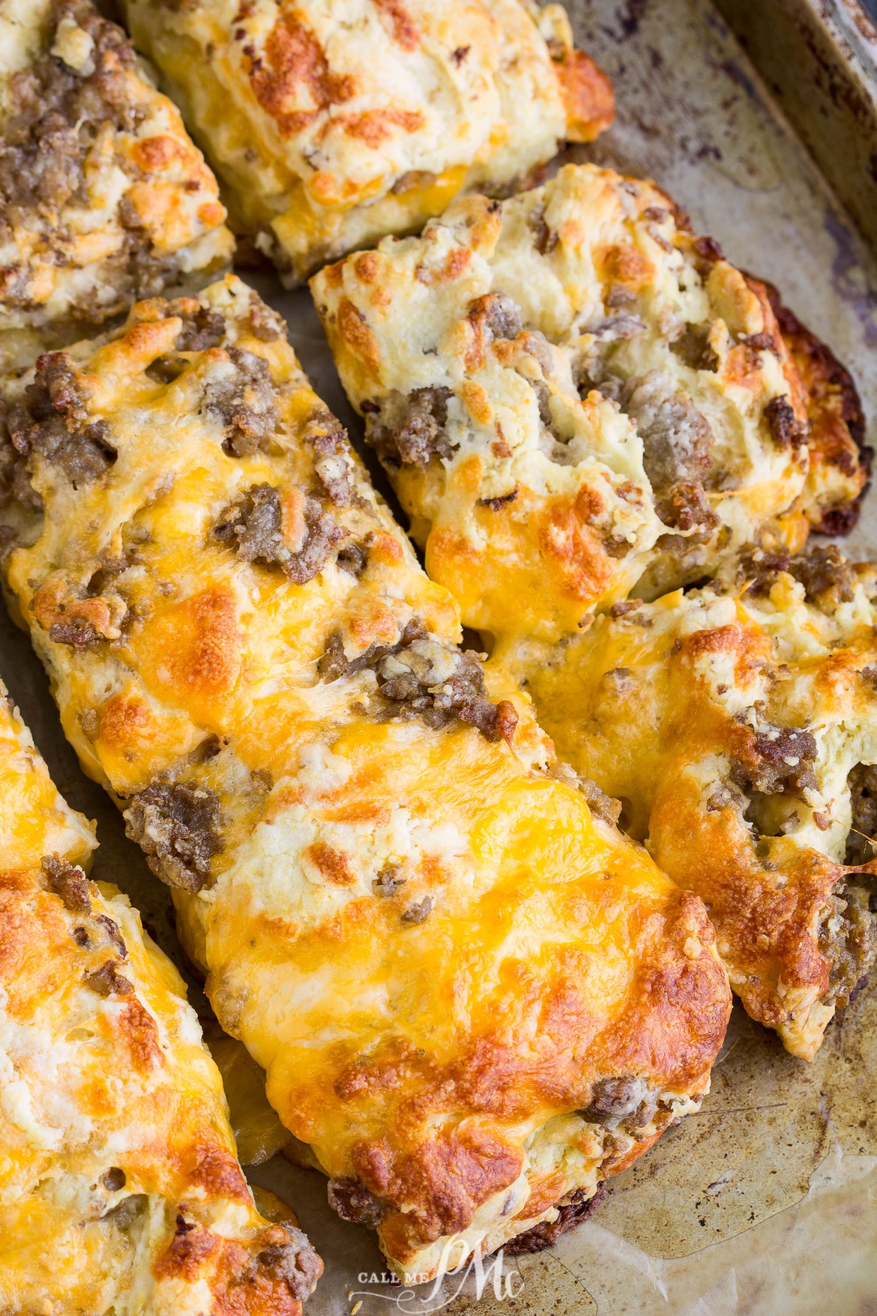 Golden-brown topped Homemade Sausage Cheddar Biscuits on a baking sheet, showcasing a crispy, melted cheese exterior and chunks of savory sausage.