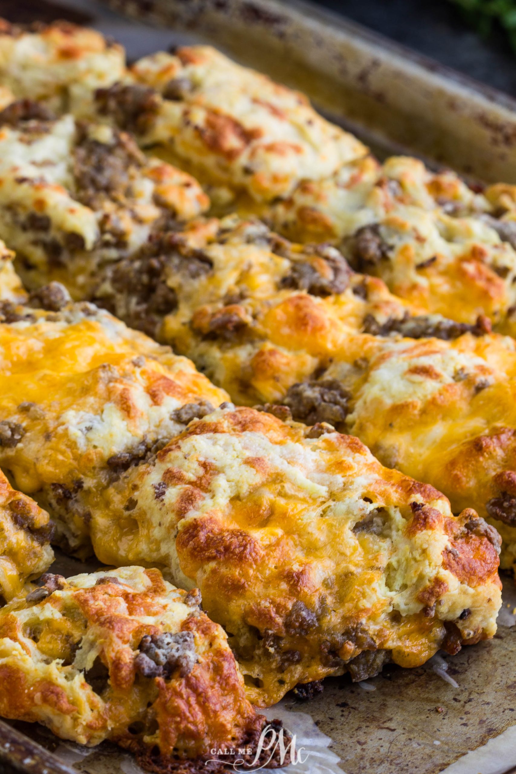 A tray of freshly baked, golden brown Homemade Sausage Cheddar Biscuits with a crispy texture.