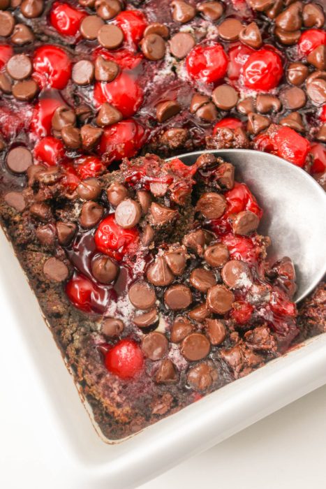 Chocolate cherry brownies in a white dish with a spoon.