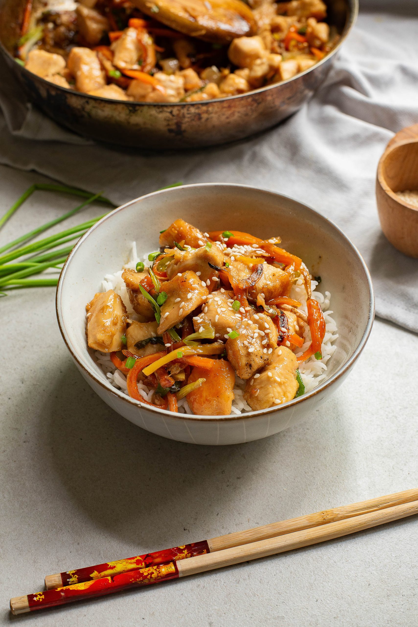Chinese chicken stir fry in a bowl with chopsticks.