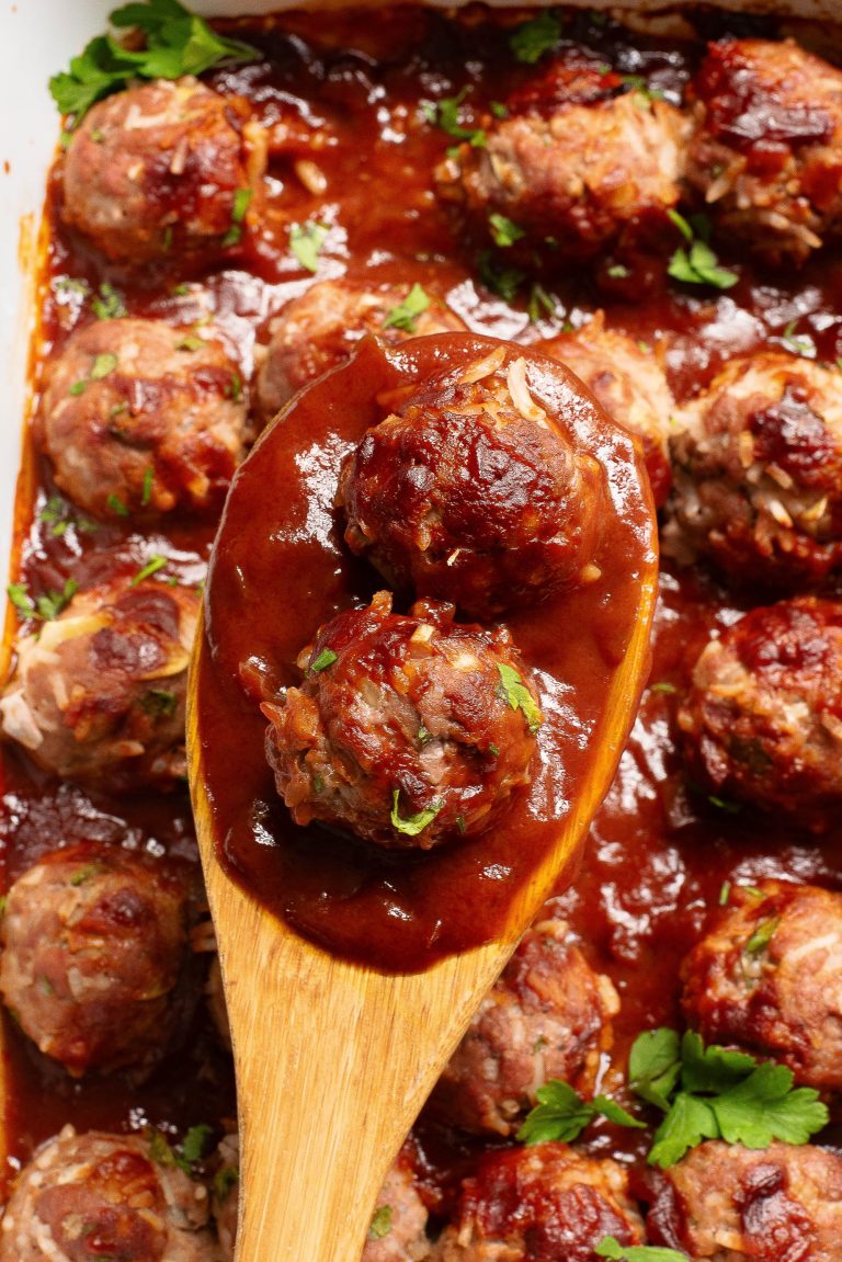 A wooden spoon with meatballs in a casserole.