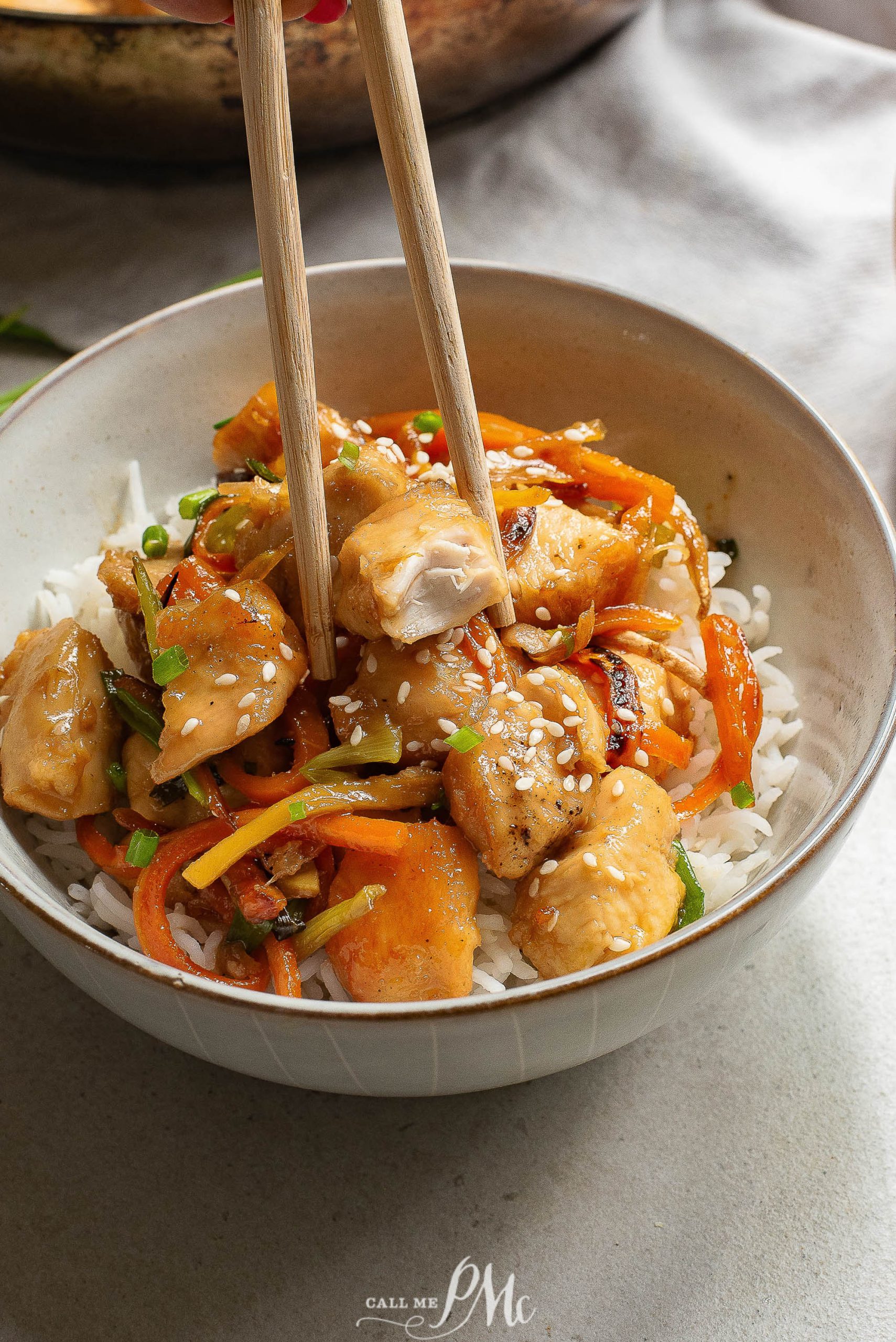 A bowl of Pineapple Chicken and vegetables over rice, garnished with sesame seeds.