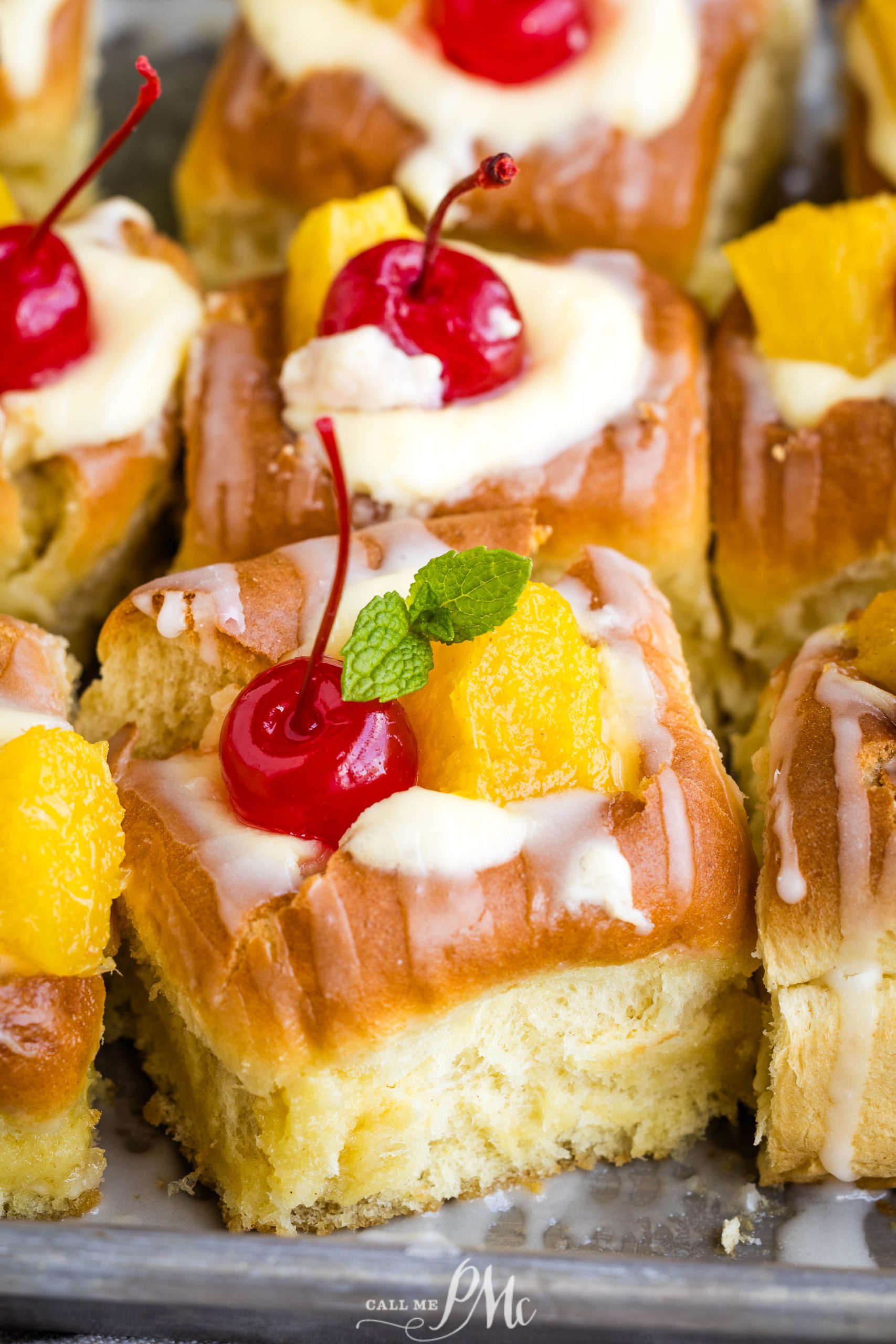 Sliced Pina Colada Cheesecake Danish topped with cream, candied fruit, and a cherry garnish.