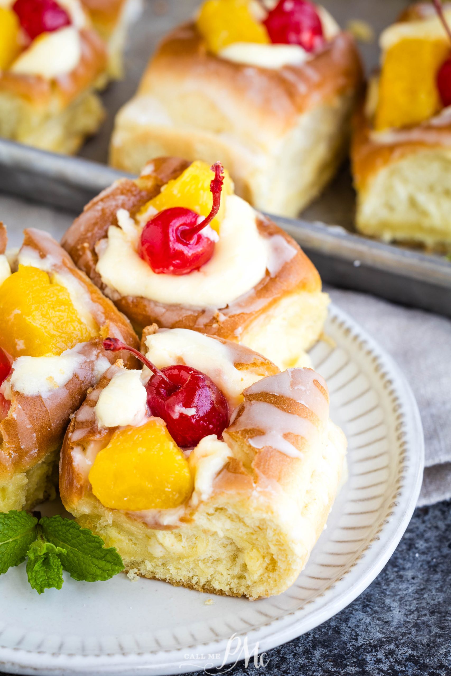 A plate of fruit-topped pastries garnished with cherries and a drizzle of icing.