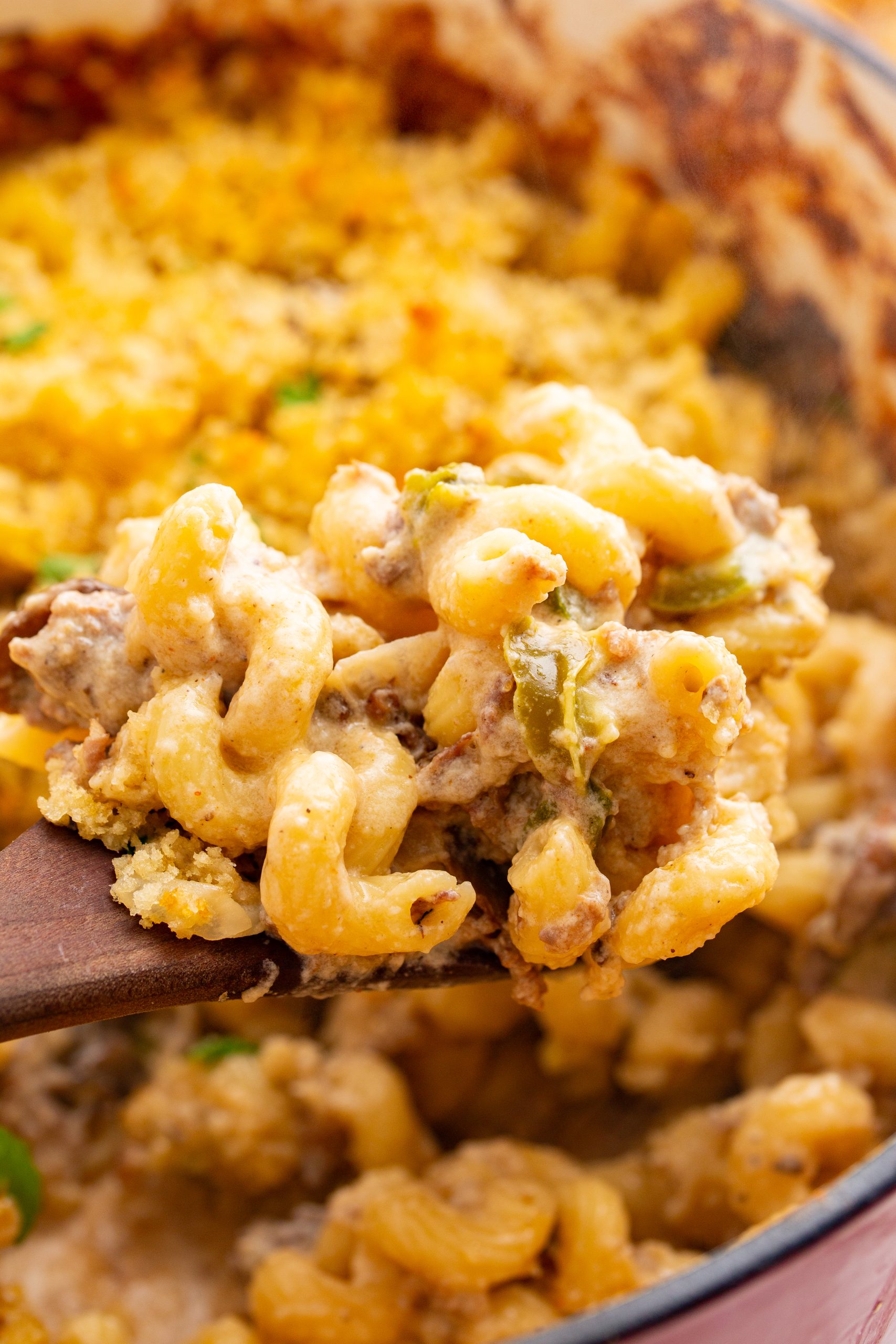 A close-up of a spoonful of creamy pasta with breadcrumbs and pieces of meat, being lifted from a pot.