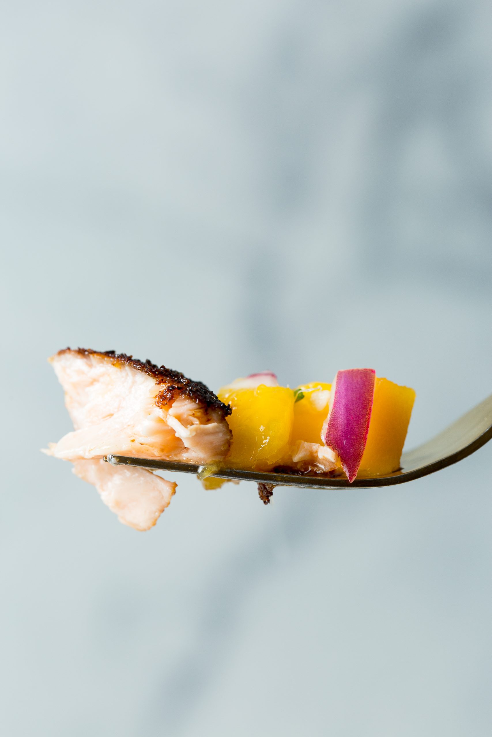 A fork holding a bite of food against a blurred background.