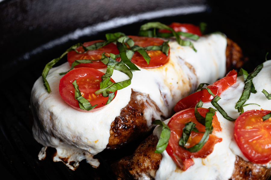 Stovetop Grilled Chicken Caprese features tender chicken breasts topped with melted mozzarella, juicy sliced tomatoes, and fresh shredded basil leaves.