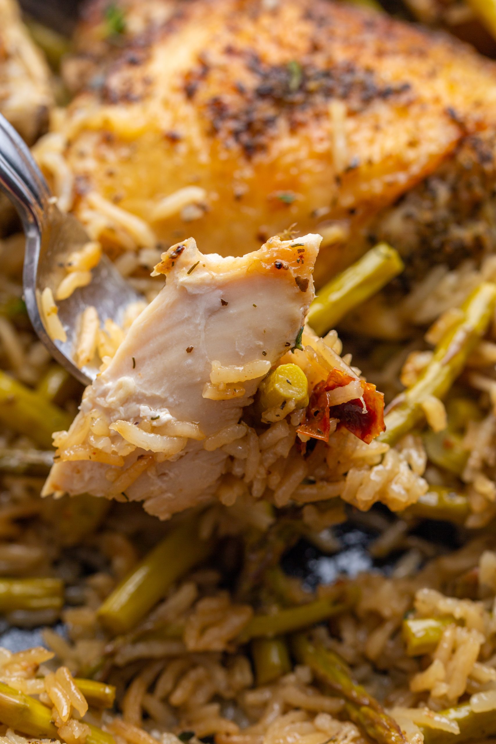 A cast-iron skillet filled with seasoned, roasted chicken thighs on a bed of rice mixed with green vegetables, garnished with thyme and lemon wedges.