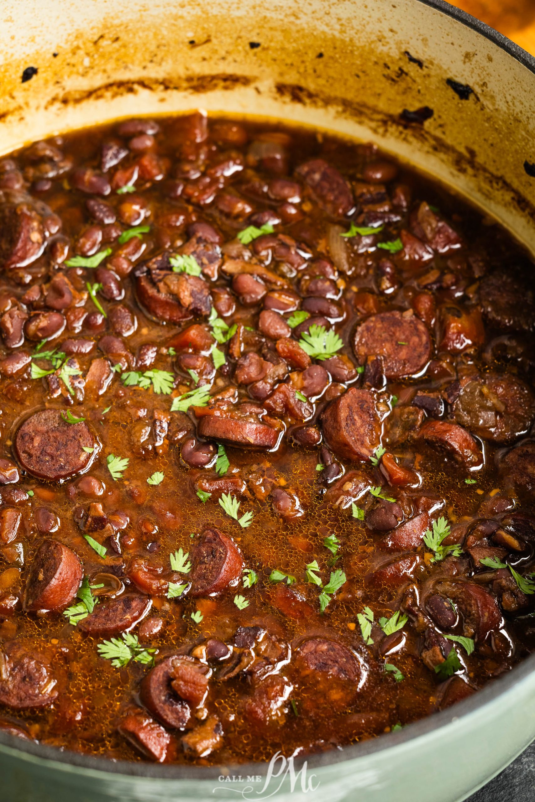 A pot filled with soup and a garnishing of fresh herbs in a savory liquid.