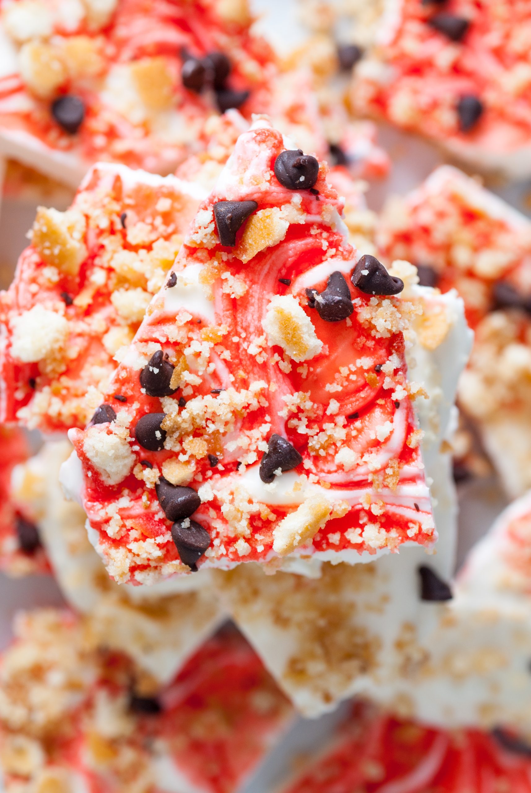 Festive strawberry swirl bark topped with crumbled cookies and dark chocolate chips.