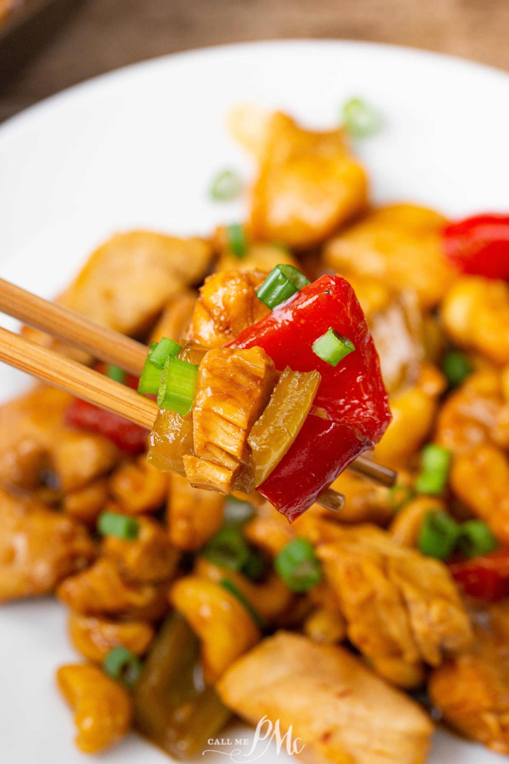 A pair of chopsticks holding a piece of stir-fried meat and veggies.