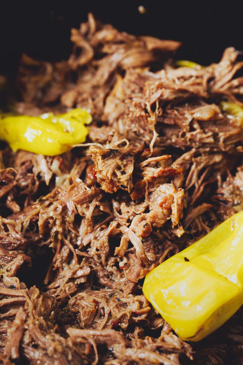 Close-up of shredded Dutch Oven Mississippi Pot Roastwith pepperoncini peppers.