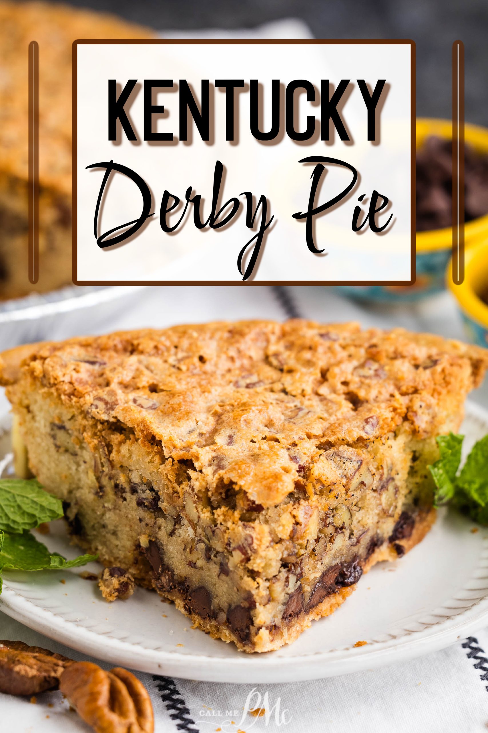 A slice of Kentucky Derby pie on a plate, featuring a flaky crust and filling with chocolate and nuts. Garnished with mint leaves, with a full pie visible in the background.