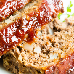 Close-up of a slice of meatloaf with a glossy glaze, showcasing the texture and ingredients. Text at the bottom reads "Easy Basic Meatloaf" with a website URL "callmepmc.com" seen beneath it.