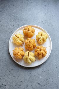 A plate with six pumpkin-shaped scones on a gray speckled countertop.