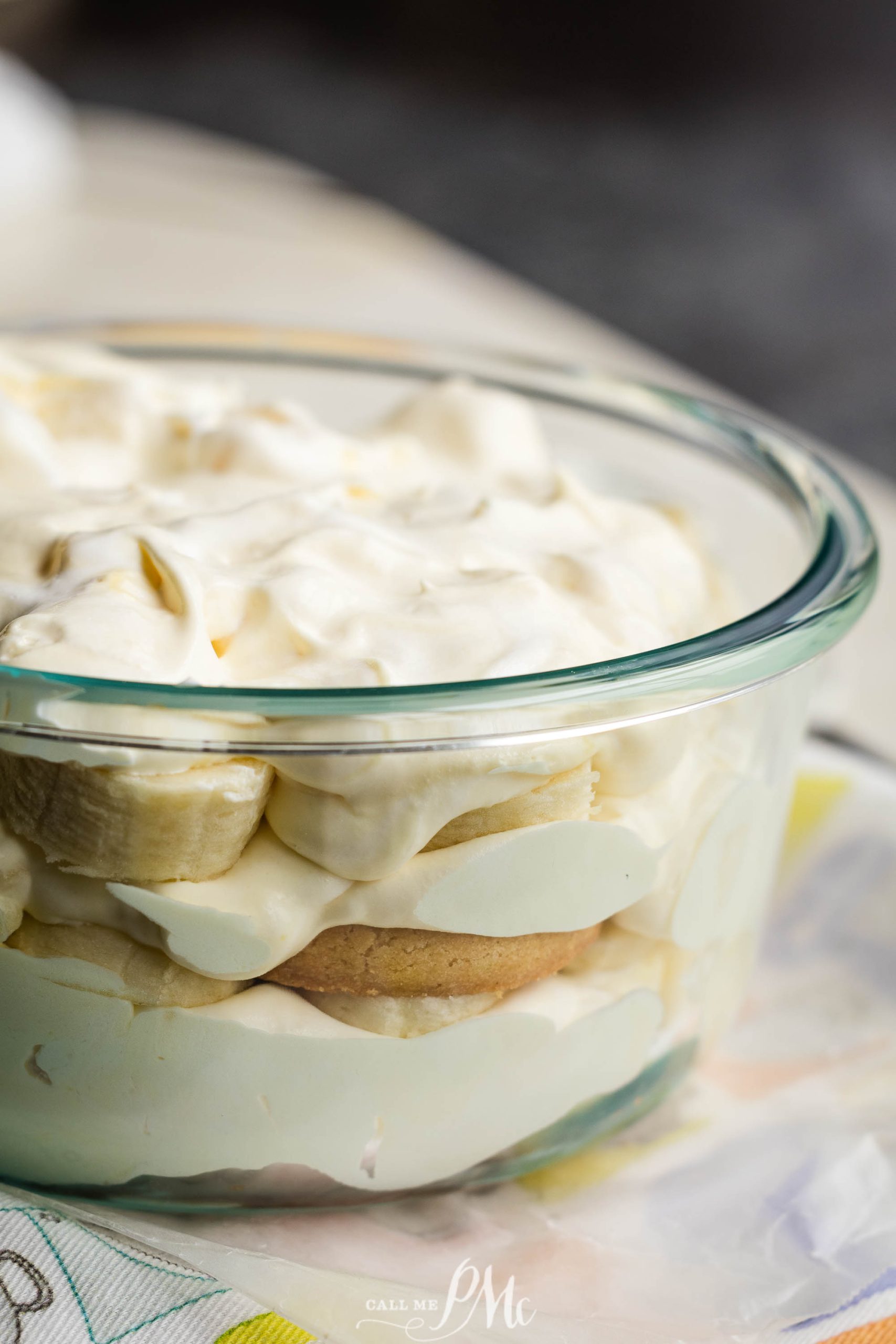 A glass dish filled with layers of banana pudding, sliced bananas, and creamy topping.