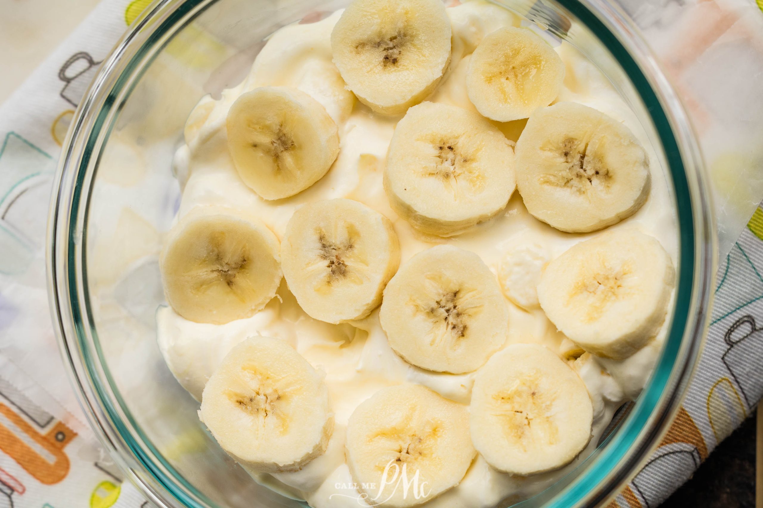 A glass bowl filled with slices of banana on top of a creamy white mixture.