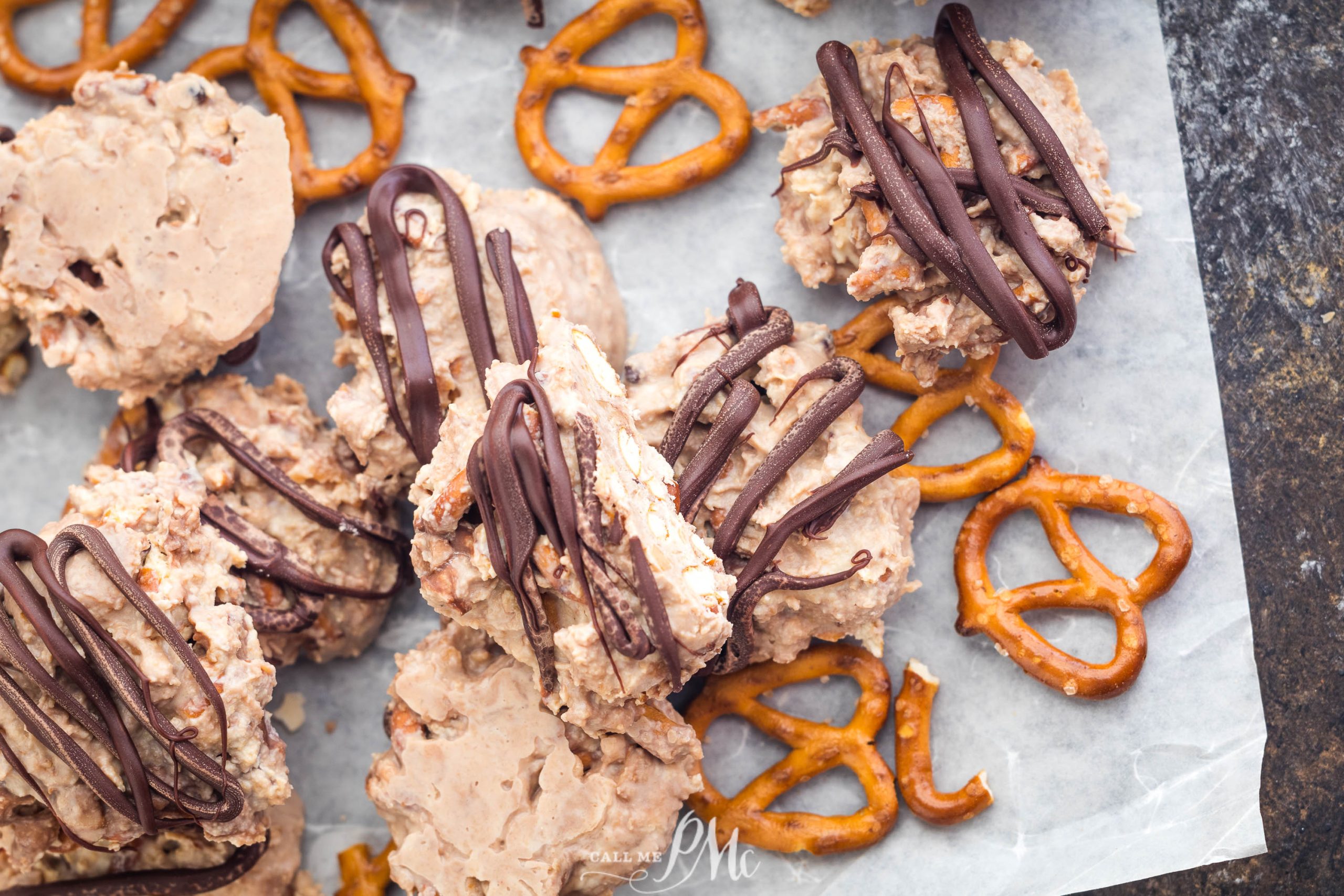 Chocolate-drizzled clusters of cookies and pretzels arranged on parchment paper.