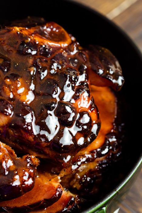 Close-up of a glazed, cooked ham with a shiny, caramelized surface in a black dish, enriched with a maple brown sugar glaze.