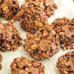 Chocolate oatmeal cookies on parchment paper, clustered together, showcasing a textured surface with visible oats and cocoa.