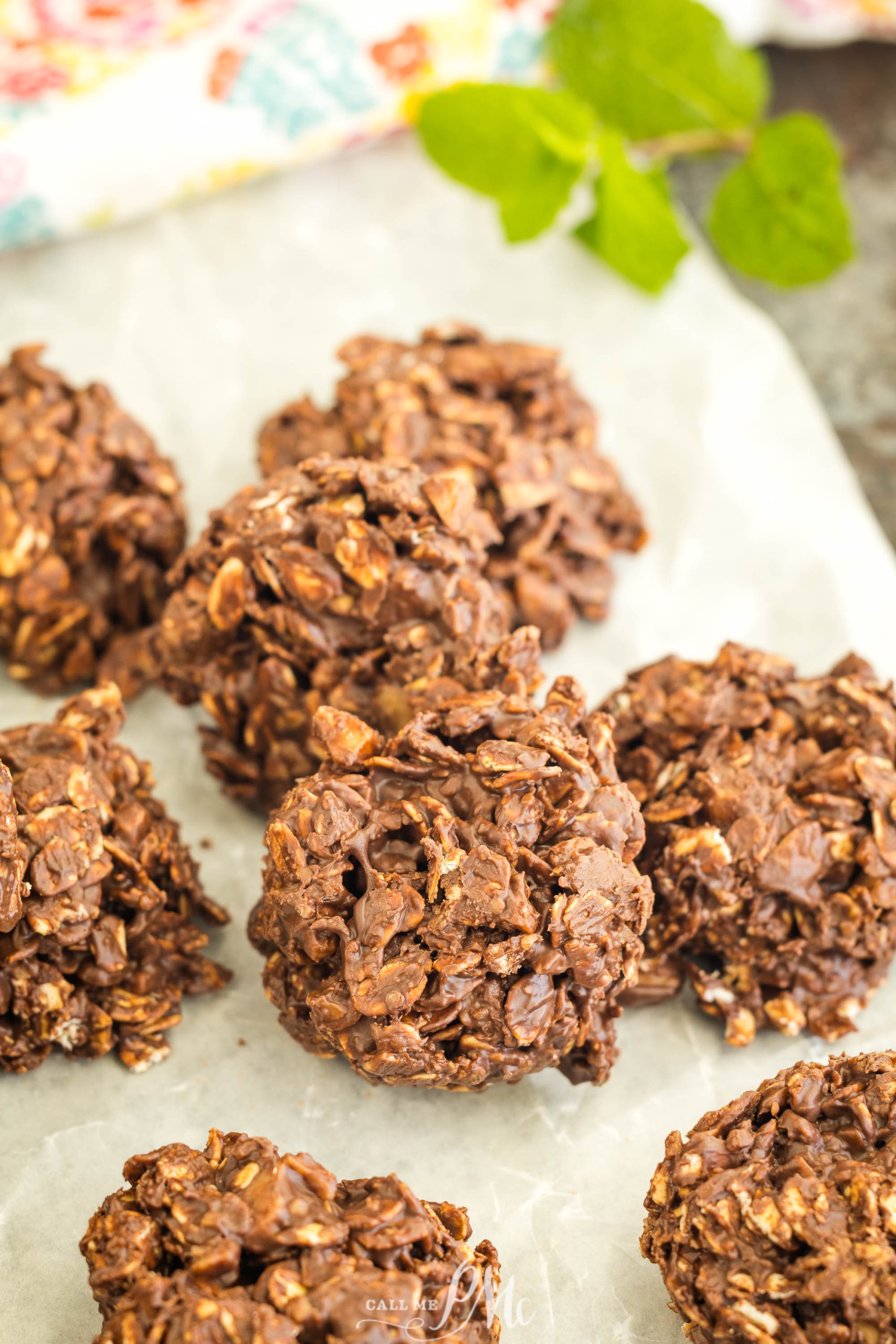 Chocolate oatmeal cookies on parchment paper with mint leaves in the background.