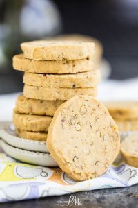 A stack of round, nutty cookies on a white plate with a colorful napkin underneath.