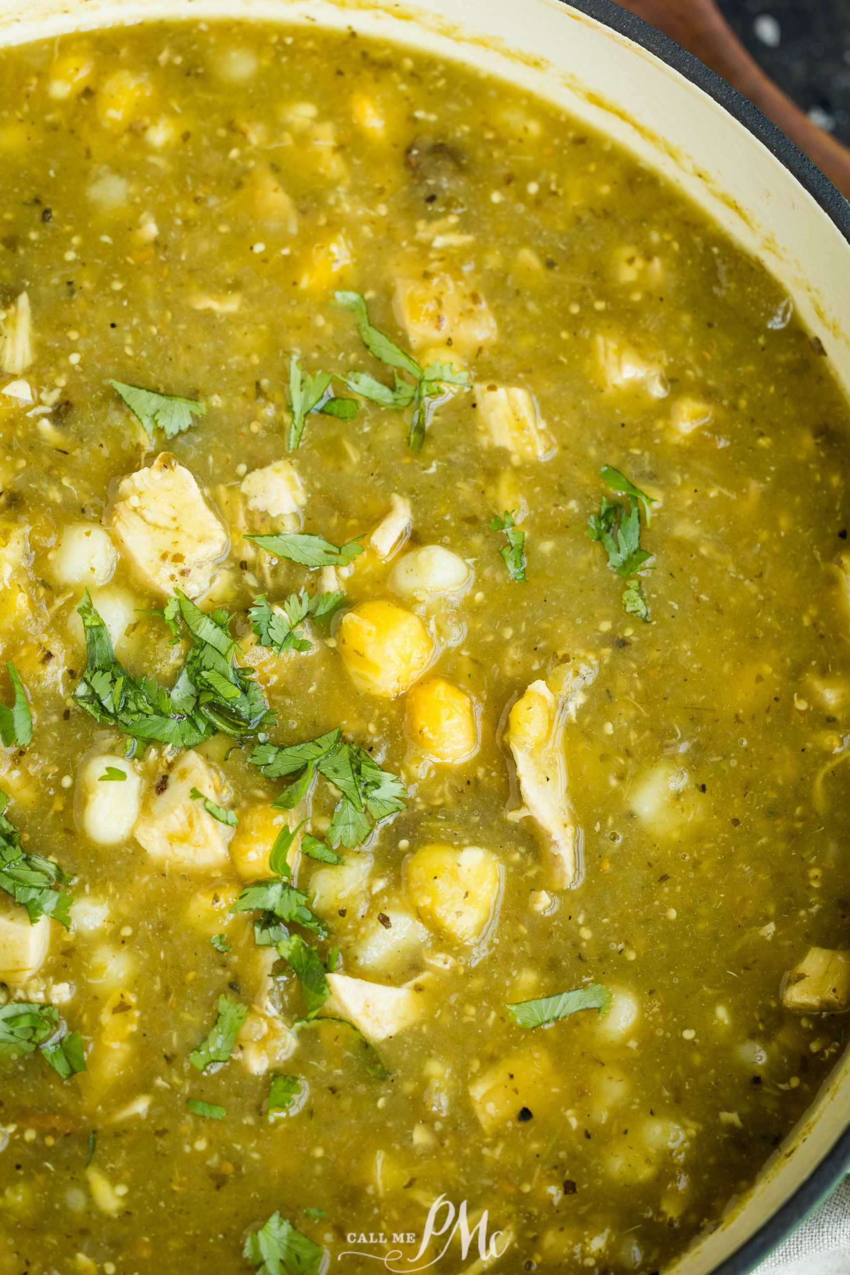 A pot of green chili stew with chicken, hominy, and cilantro.