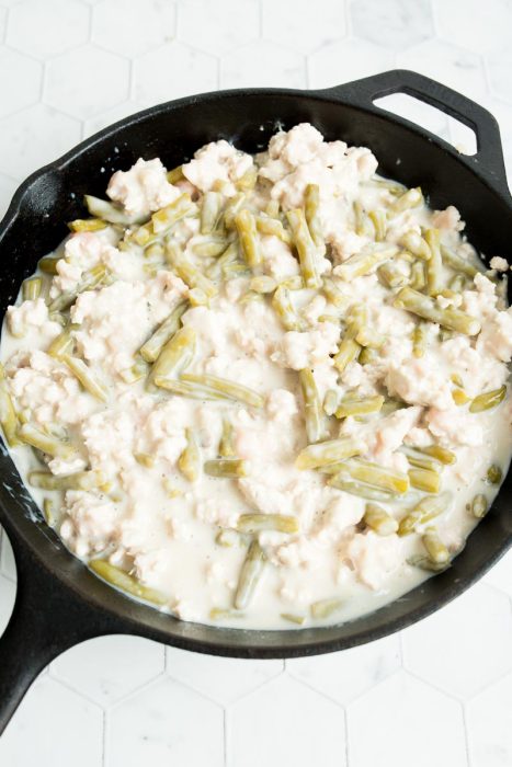 A skillet filled with green beans and a creamy white sauce.