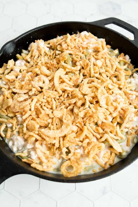 A skillet filled with a creamy casserole topped with crispy fried onions.