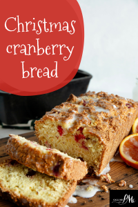 A delightful loaf of Christmas cranberry bread rests on a wooden board, with slices invitingly cut. Perfect for holiday gatherings, this treat embodies the festive essence of a cherished Christmas cranberry bread recipe.