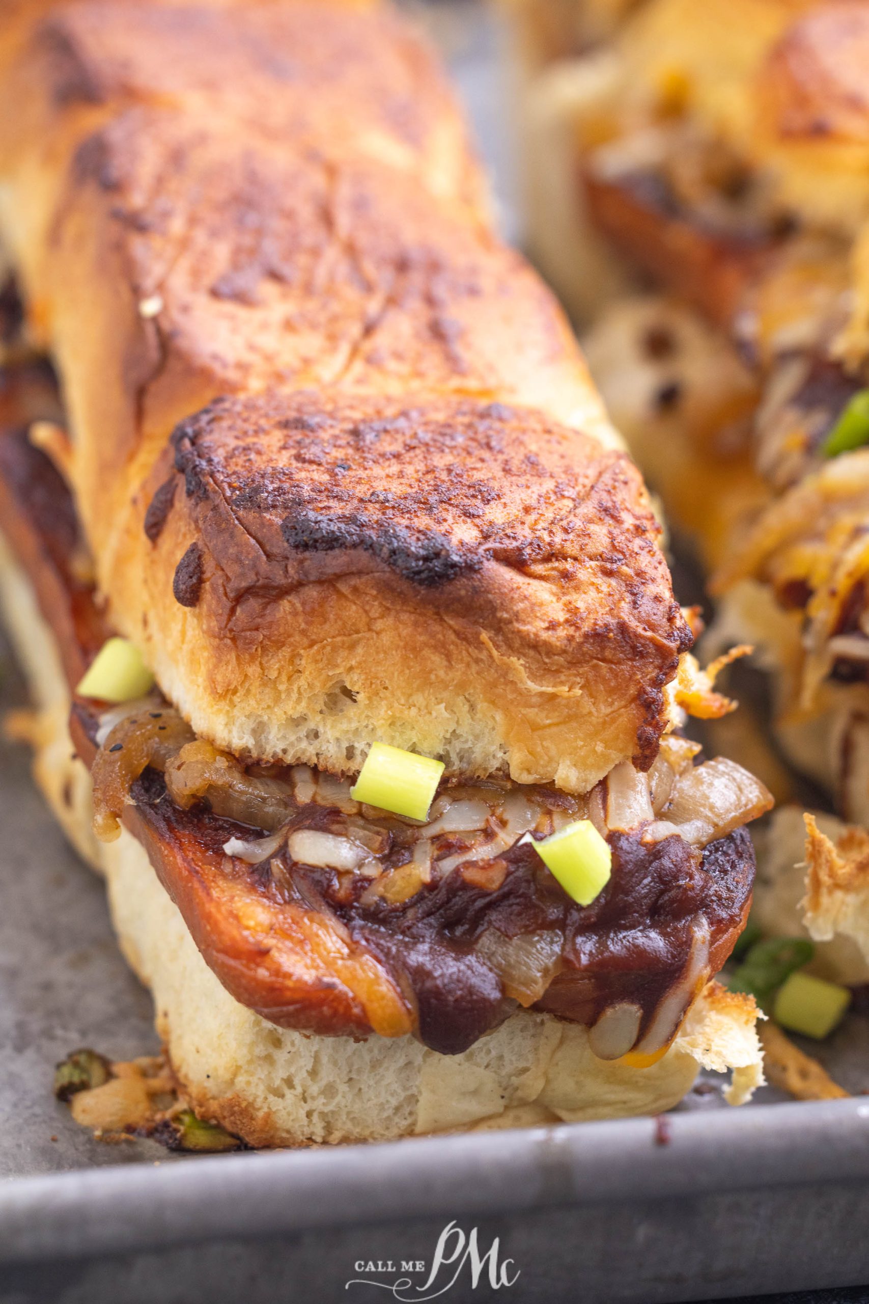 Close-up of a toasted sandwich loaded with caramelized onions and chopped green onions on a crusty bread.