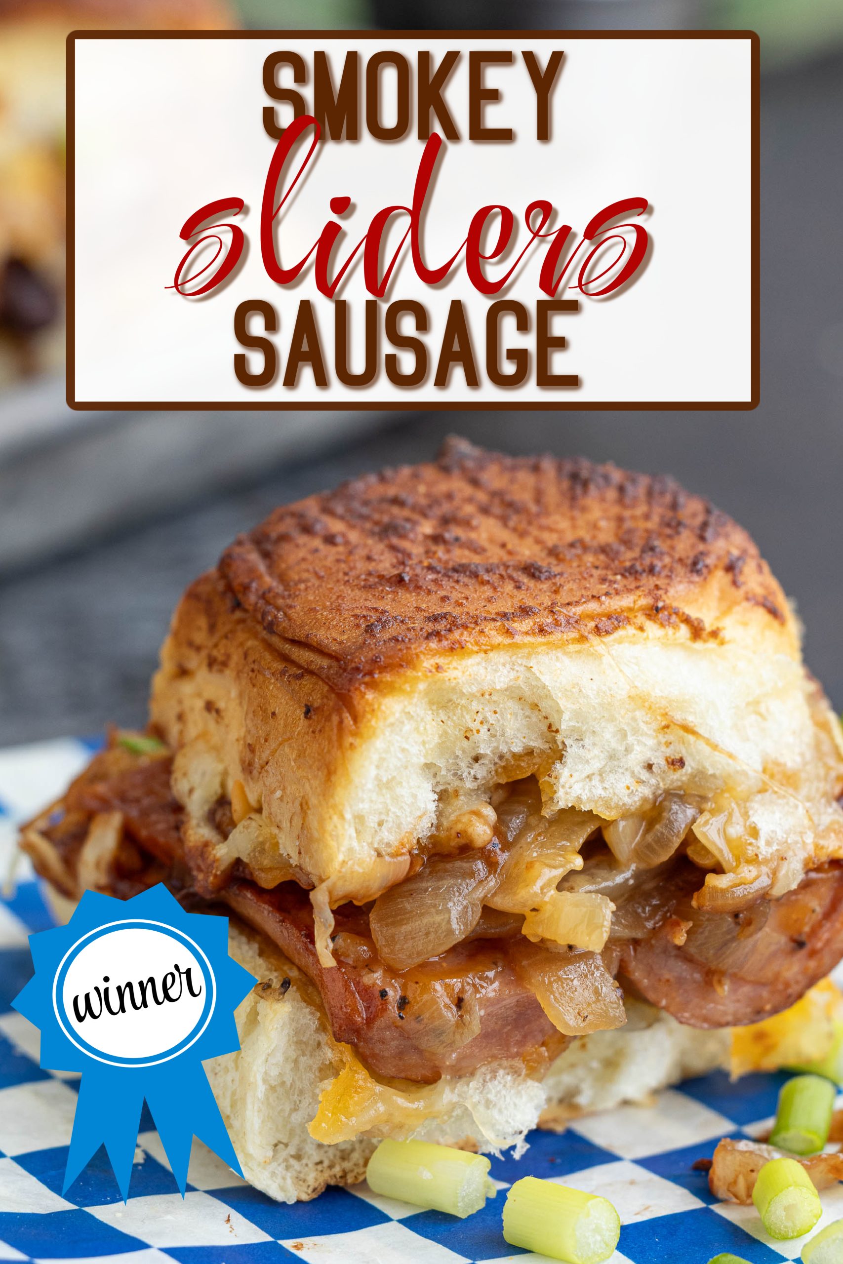 Caramelized Onion Sausage Dog Sliders: A savory sausage slider topped with sweet caramelized onions, perfectly nestled on a bun. Displayed on blue checkered paper, the winning creation is adorned with a "winner" ribbon.