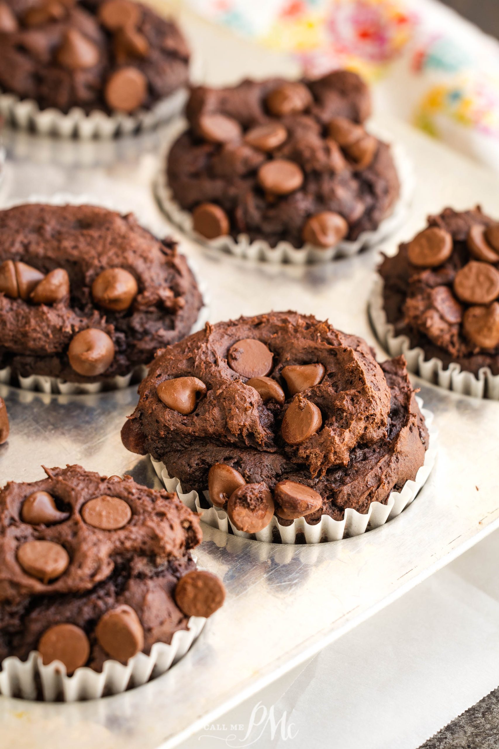 3 Ingredient Pumpkin Brownie Muffins with chocolate chips on a metal tray lined with white paper cups.