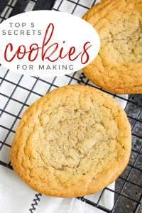 Two large cookies on a cooling rack with a text overlay reading "5 Secrets to Baking the Best Cookies.