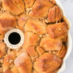 Close-up view of a baked monkey bread in a bundt pan, showing golden brown dough pieces with visible nuts and a sugary glaze.