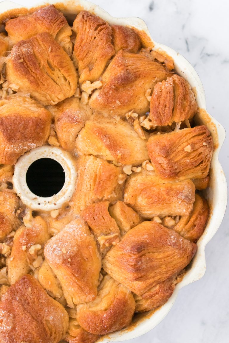 Close-up view of a baked monkey bread in a bundt pan, showing golden brown dough pieces with visible nuts and a sugary glaze.