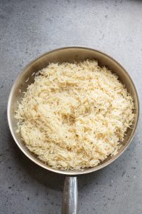 A pan filled with cooked basmati rice on a gray countertop.