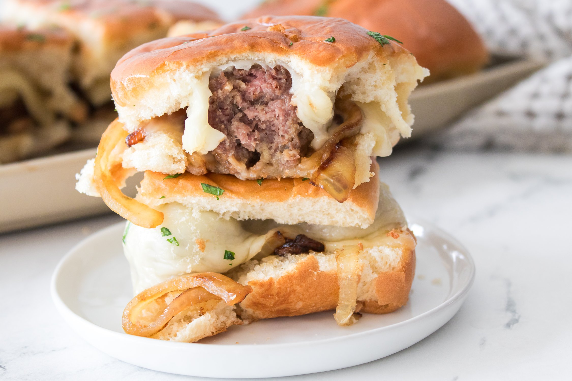 A cross-section of a beef burger with melted cheese and caramelized onions, served on a plate.