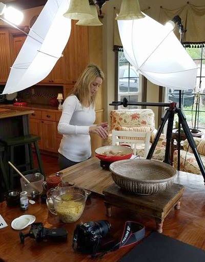 A woman expertly prepares food in a kitchen with a professional lighting setup, embodying the 10 essentials for amazing photos. The camera rests on the table, perfectly capturing her movements, while the mixing bowl and ingredients add depth to this beautiful scene.