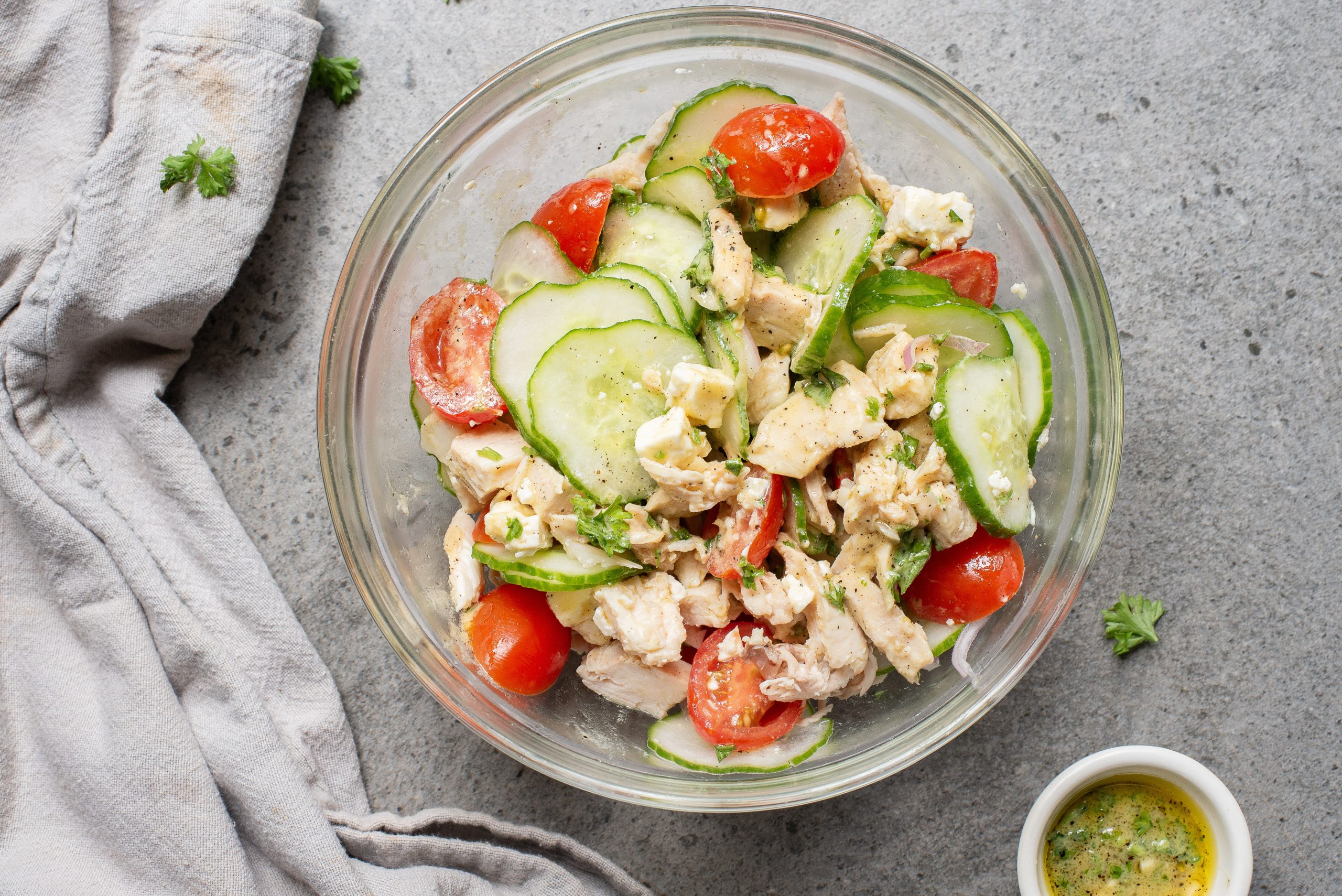 A clear bowl of food on a gray surface.