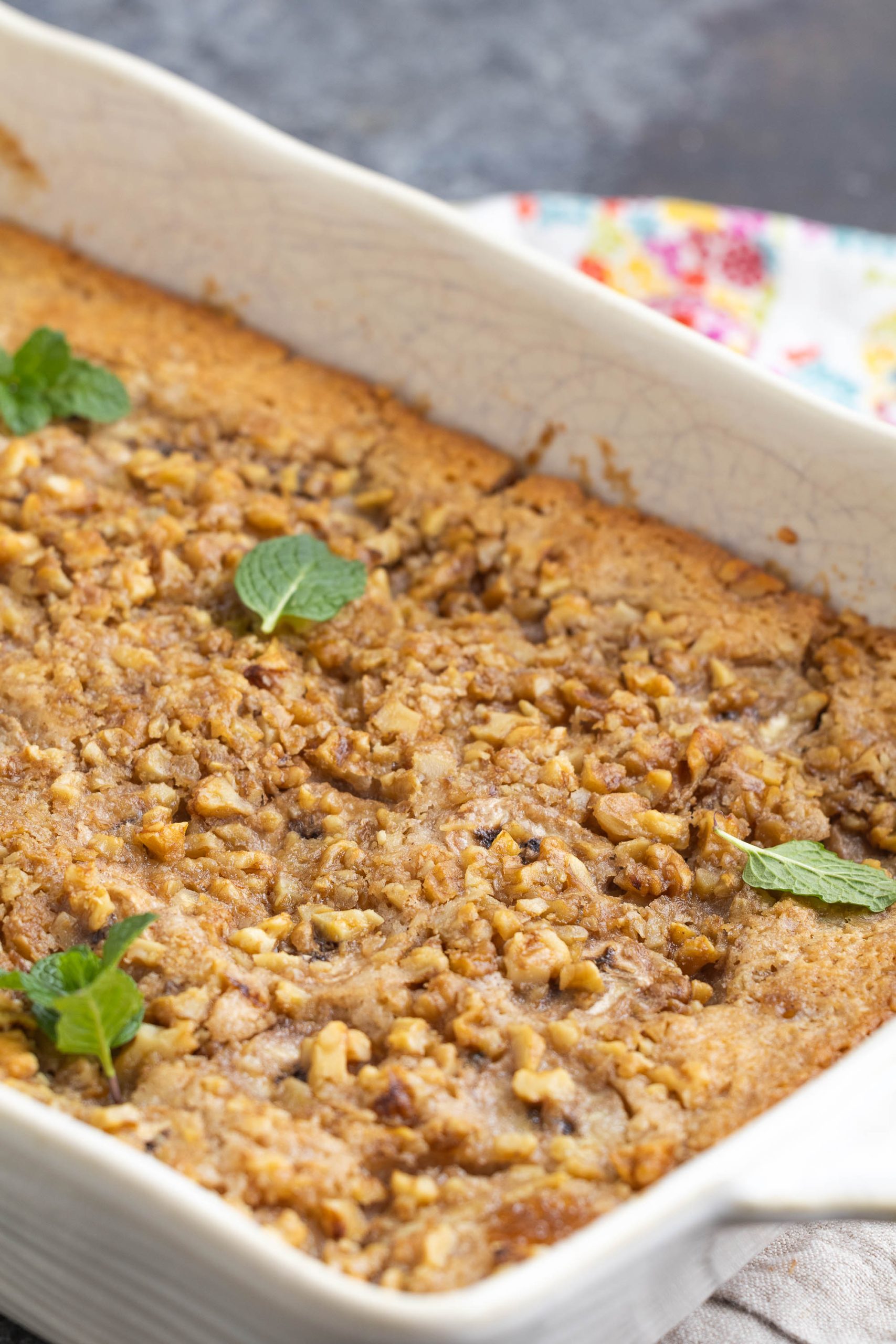 Baked dish with a crumbly walnut topping in a rectangular dish, garnished with a few mint leaves.