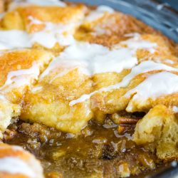 A close-up of a Crescent Roll Coffee Cake reveals its golden-brown crust, elegantly drizzled with white icing, all nestled in a round dish.