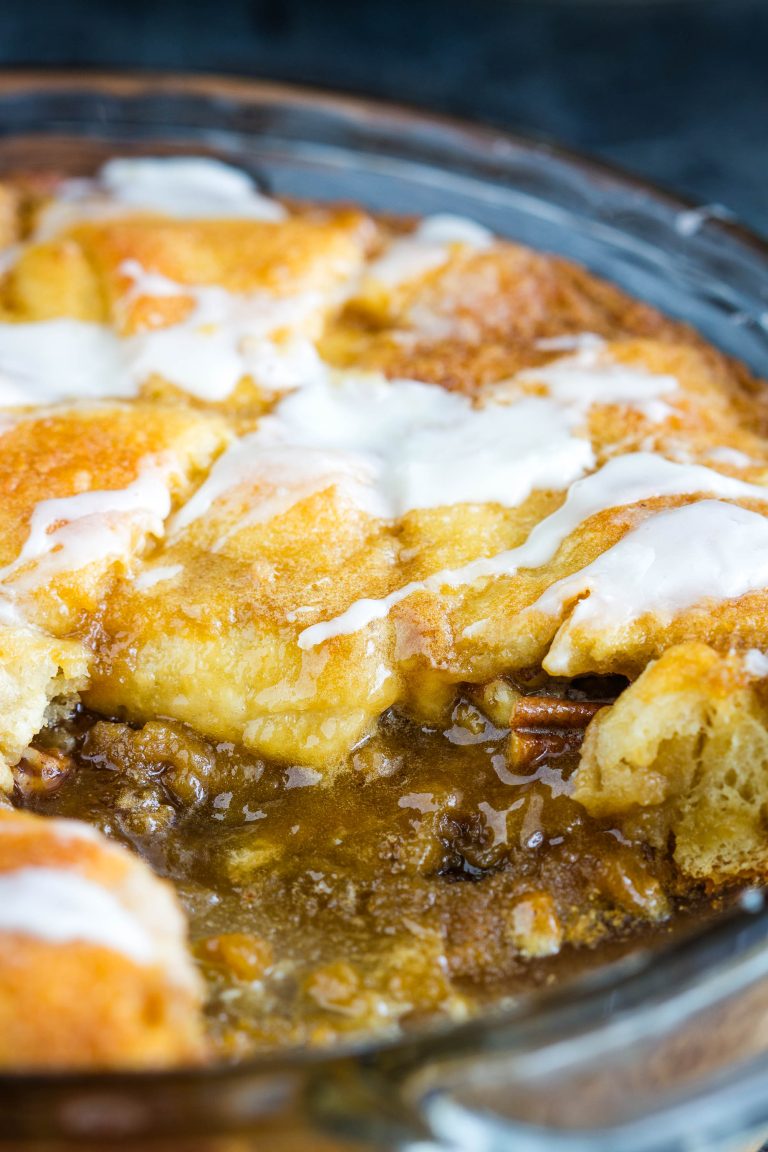 A close-up of a Crescent Roll Coffee Cake reveals its golden-brown crust, elegantly drizzled with white icing, all nestled in a round dish.